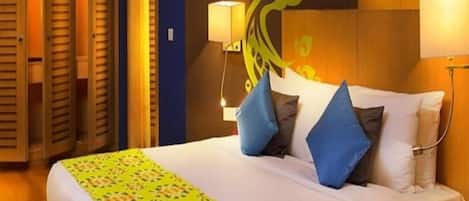 Habitación de hotel con una cama grande, dos lámparas de noche, un teléfono y una pared con diseño decorativo.