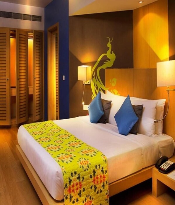 A hotel room with a large bed, two bedside lamps, a telephone, and a wall with a decorative design. - The Beatle (Mumbai)