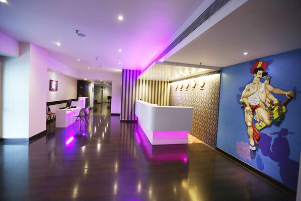 A modern hotel lobby with a reception desk, a patterned wall, and a large mural. - The Beatle (Mumbai)