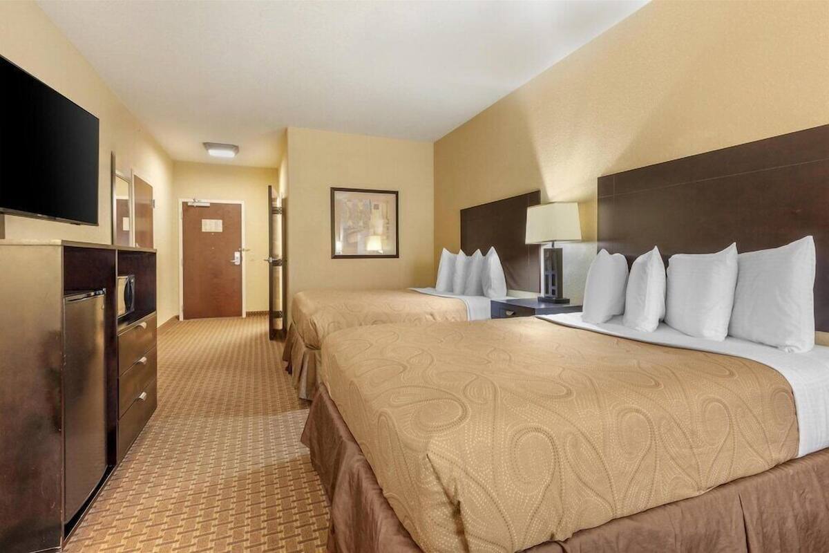 A hotel room with two beds, a TV, a desk, and a bathroom.