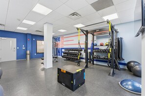 A gym with exercise equipment, a wall with motivational text, and a rack of dumbbells.