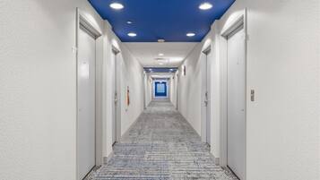 Un pasillo de hotel con paredes blancas, techo azul y piso alfombrado.