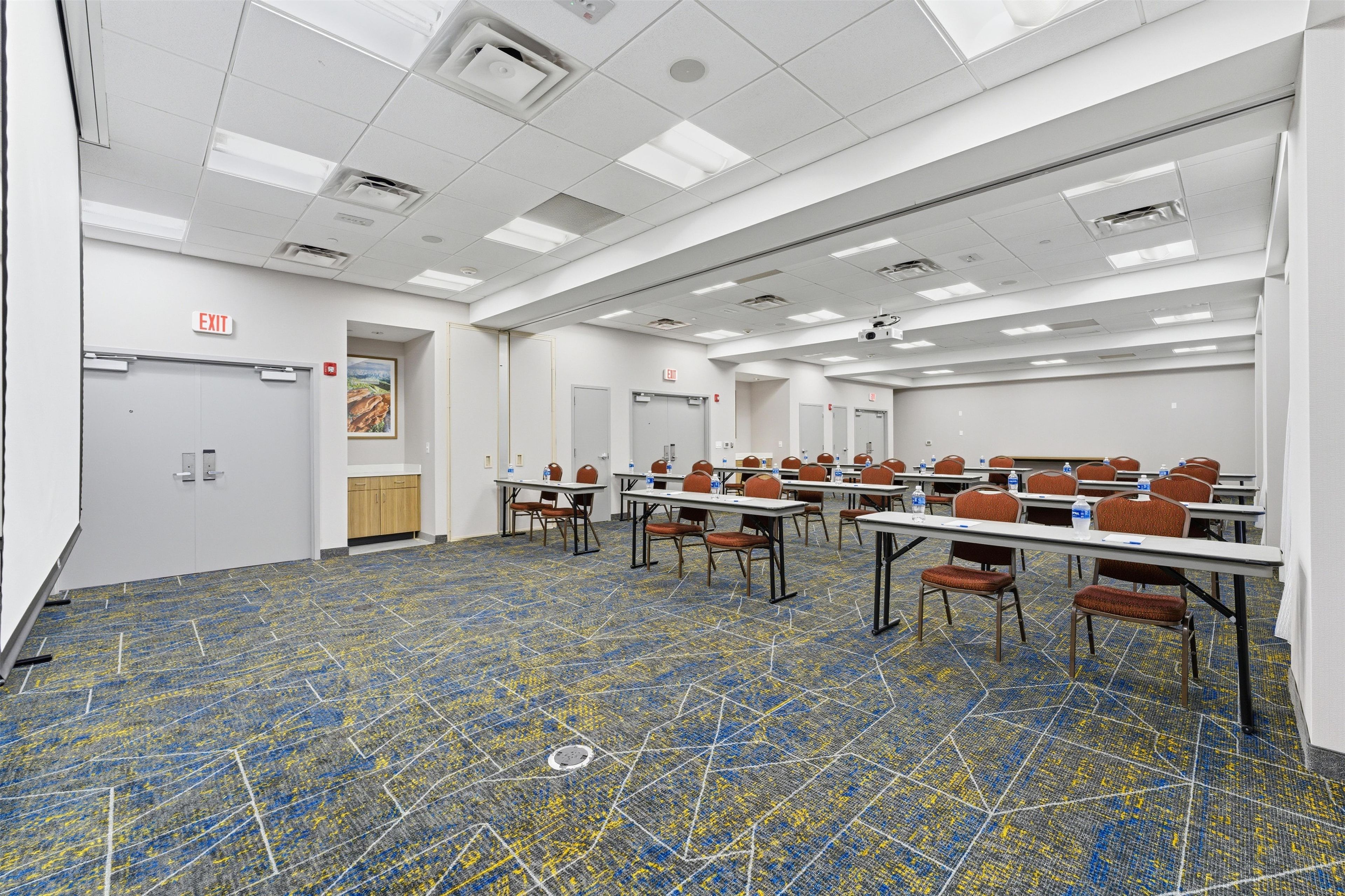 A conference room with tables, chairs, and an exit door.