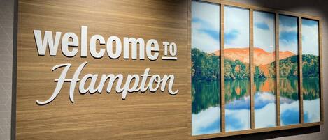A welcome sign with 'welcome to Hampton' and a scenic lake view.