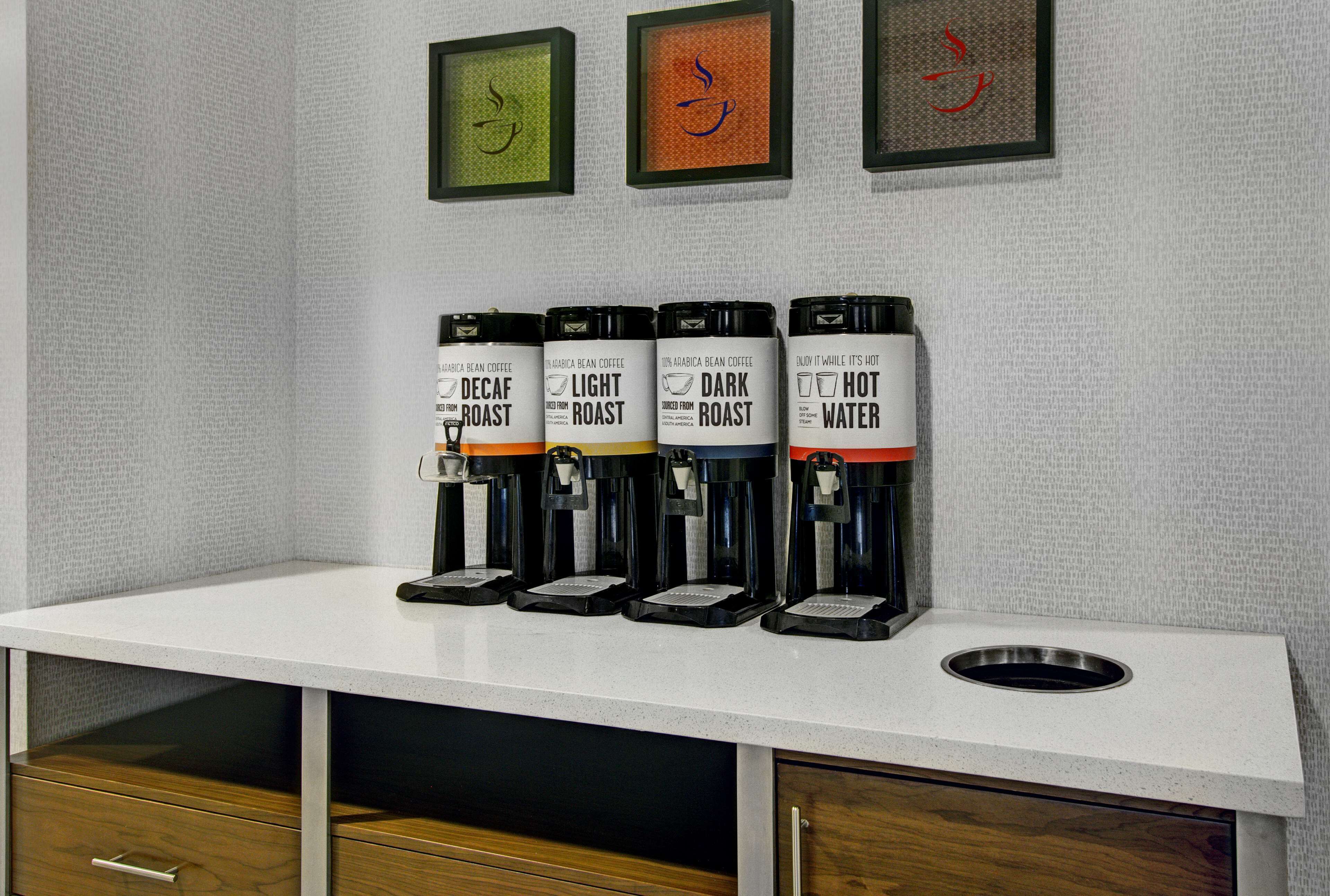 A coffee station with four dispensers labeled 'Decaf Roast,' 'Light Roast,' 'Dark Roast,' and 'Hot Water.'