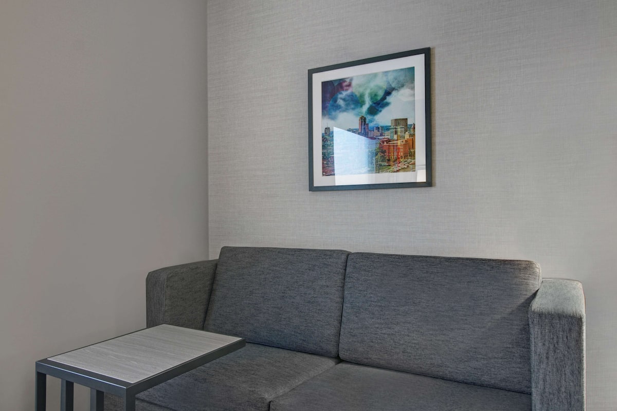 A grey sofa with a framed artwork on the wall above it.