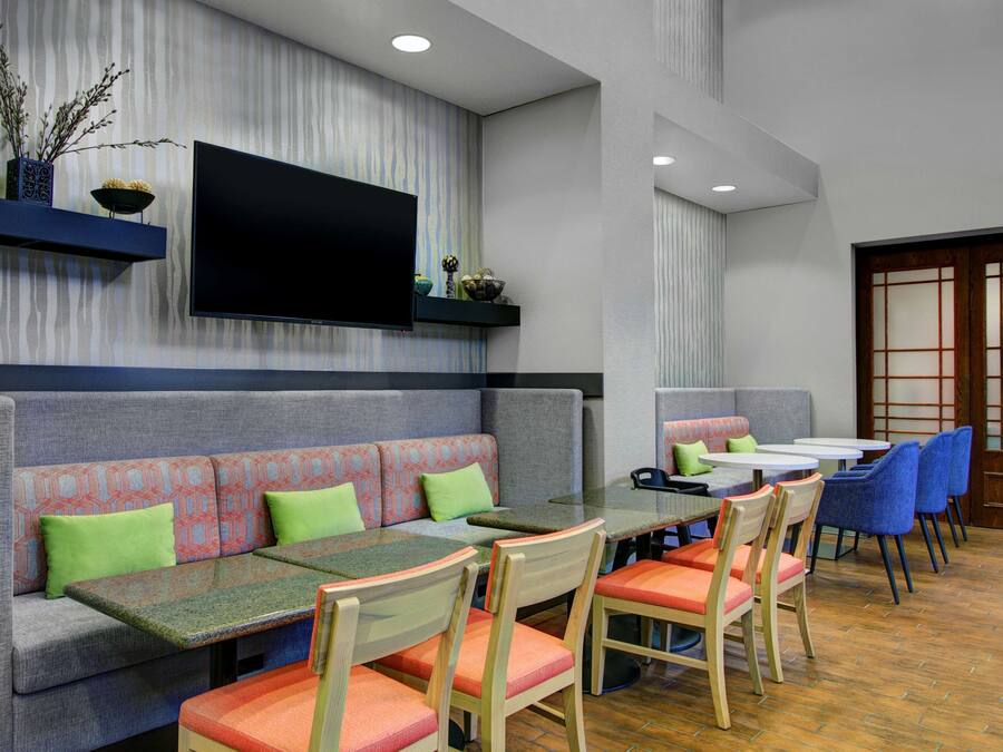 A restaurant with a long counter, cushioned seating, and a flat-screen TV mounted on the wall.