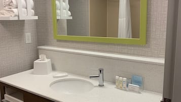 A modern bathroom with a white sink, a mirror with a green frame, and a towel rack.