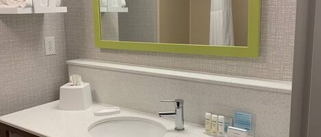A modern bathroom with a white sink, a mirror with a green frame, and a towel rack.