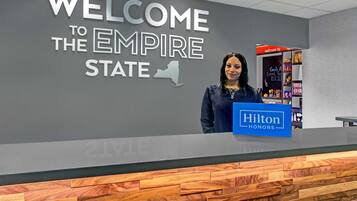 Un comptoir d’accueil avec une pancarte indiquant « BIENVENUE À L’EMPIRE STATE » et une autre pancarte « Hilton Honors ».