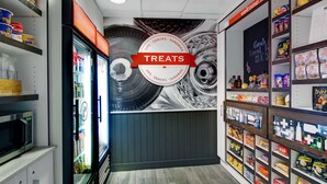 Una sección de snacks con diversas opciones, incluyendo papas fritas y dulces, además de un refrigerador con bebidas.