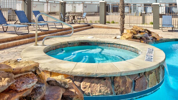 A circular hot tub surrounded by stone steps and a pool. - La Quinta Inn & Suites by Wyndham Dallas Grand Prairie South (Grand Prairie)