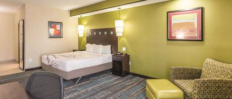 A hotel room with a bed, a desk, a chair, and a small table.