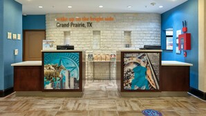 A reception desk with a stone wall backdrop and a sign reading "wake up on the bright side Grand Prairie, TX". - La Quinta Inn & Suites by Wyndham Dallas Grand Prairie South (Grand Prairie)