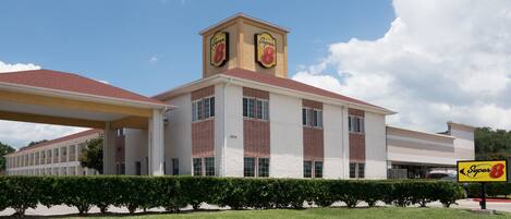 A Super 8 hotel with a central tower, brick facade, and a covered parking area.