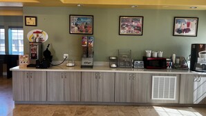 A breakfast bar with a coffee machine, a toaster, and a kettle. There are framed pictures on the wall above the bar. - Super 8 by Wyndham Rosenberg TX (Rosenberg)