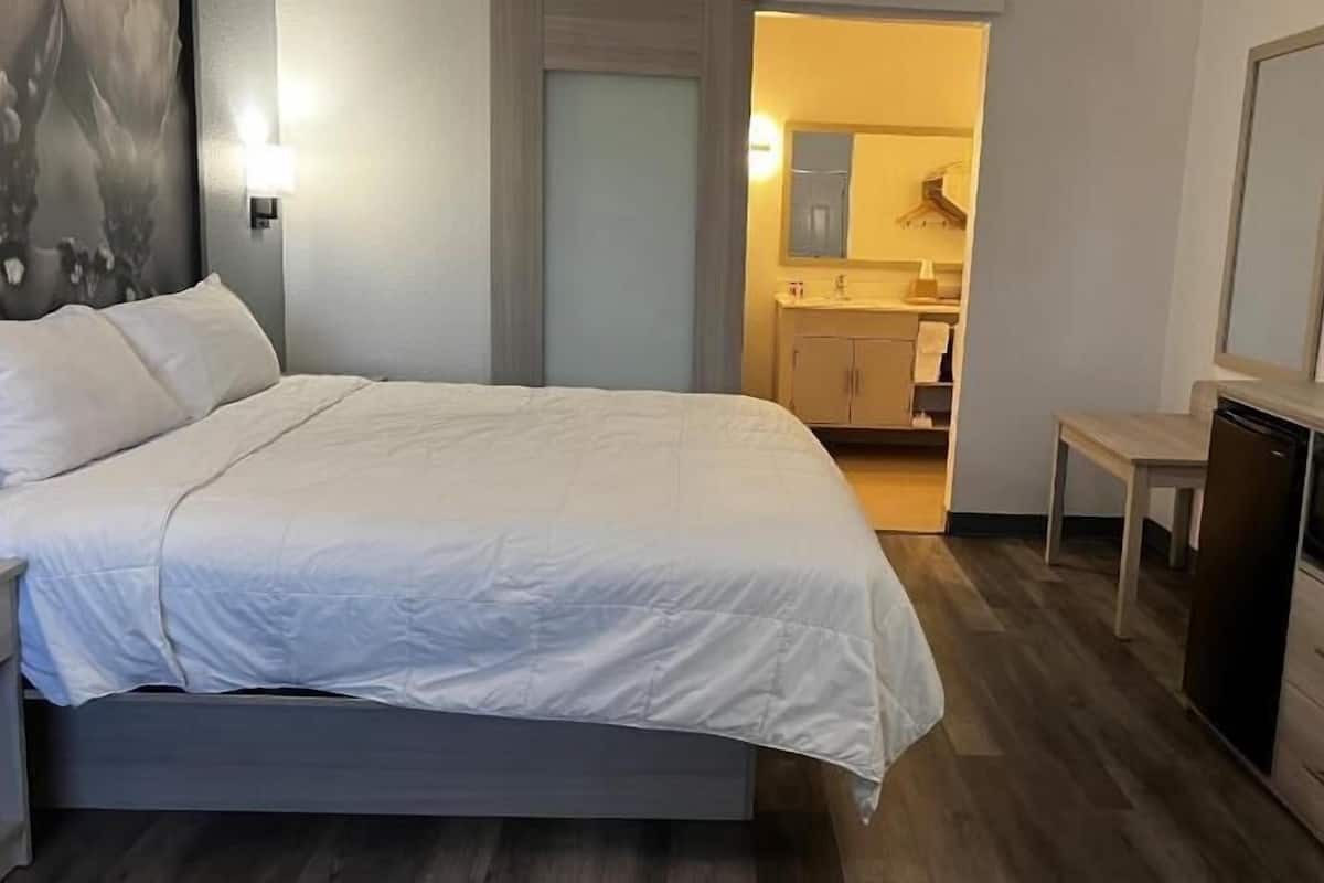 Quarto de hotel com cama, televisão, mesa pequena e micro-ondas.