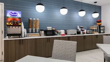 A modern kitchen area with a coffee machine, microwave, and various food items on the counter.