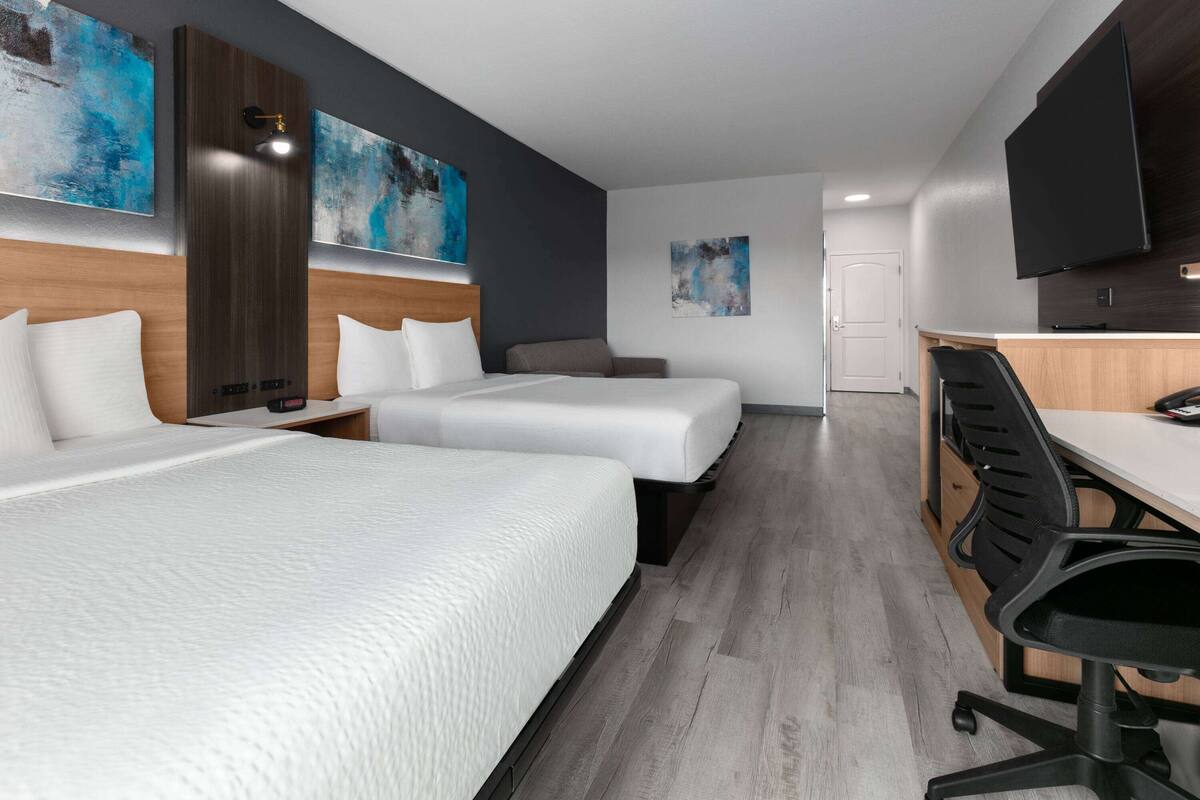 Quarto de hotel com duas camas, uma escrivaninha e uma televisão.