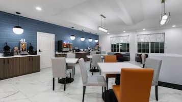 A modern restaurant with a blue wall, white ceiling, and a variety of seating options including tables and chairs.