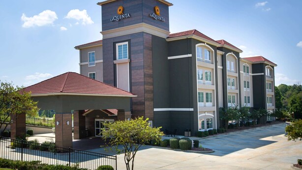 A multi-story hotel with a prominent entrance, a covered patio area, and a landscaped courtyard. - La Quinta Inn & Suites by Wyndham Tupelo (Tupelo)
