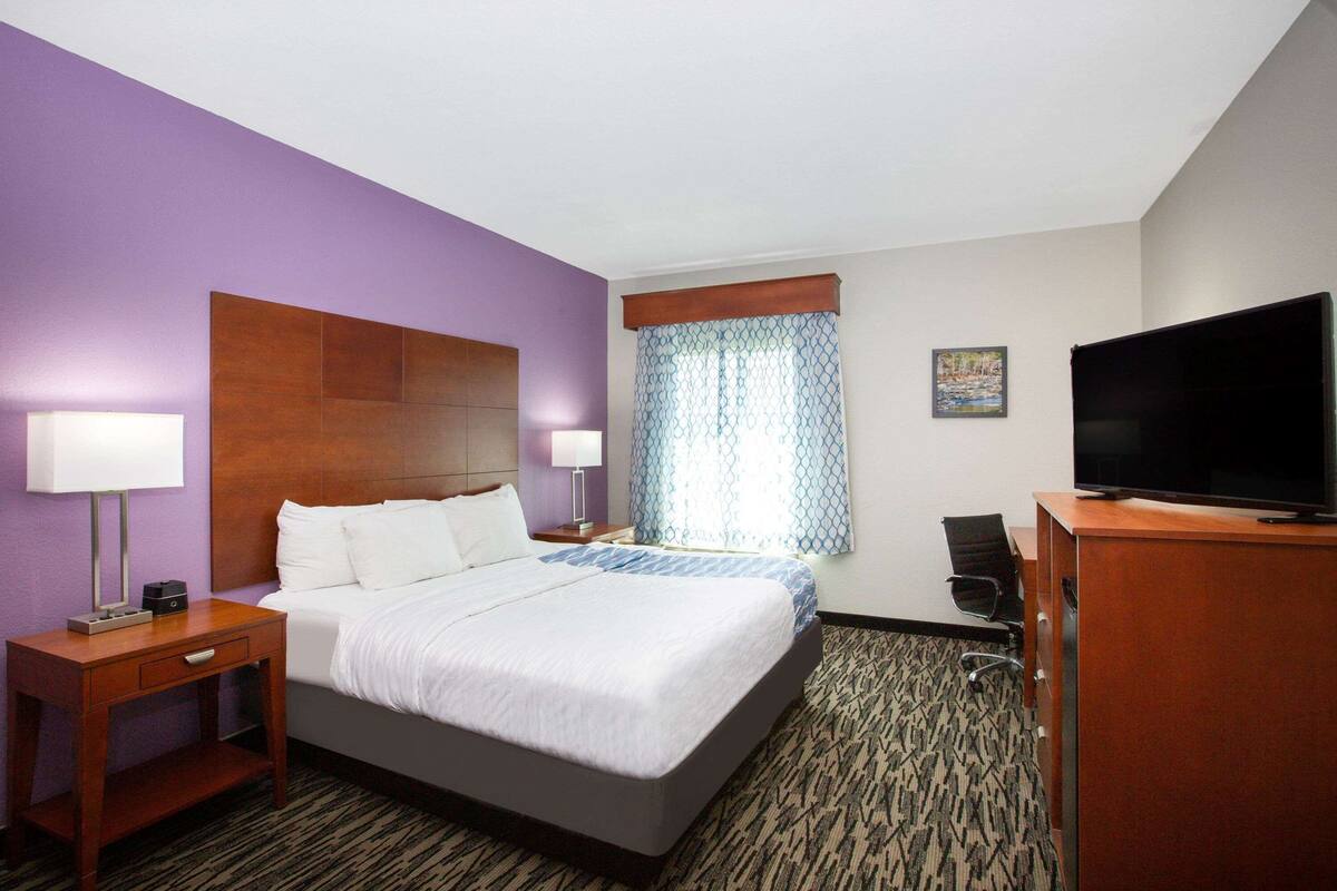 A hotel room with a bed, nightstands, a TV, and a desk.