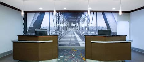 A reception area with a large window view of a bridge, two reception desks, and a patterned carpet.