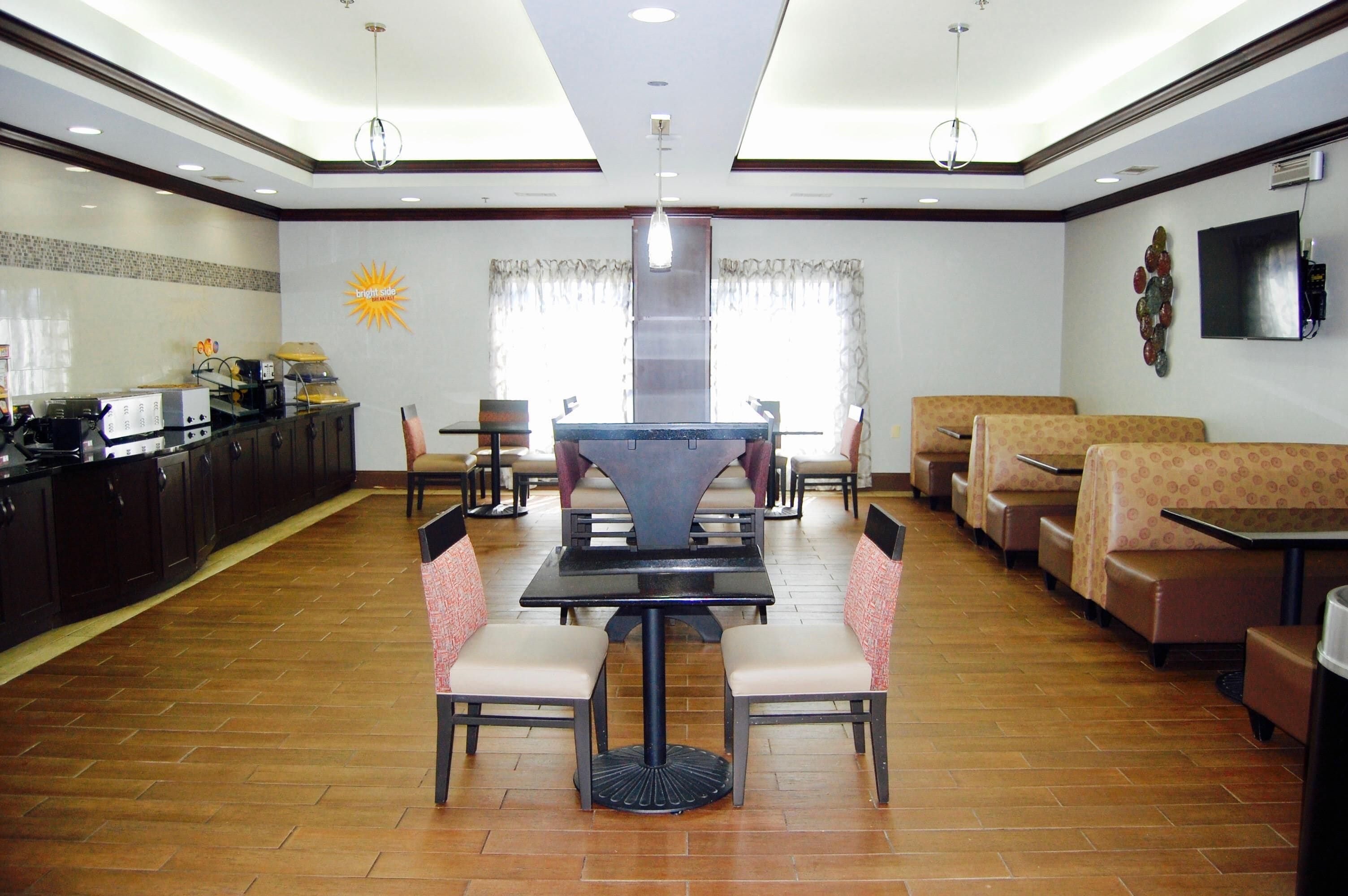 A restaurant with a central dining table, booths, and a kitchen area.