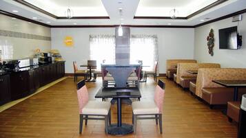 A restaurant with a central dining table, booths, and a kitchen area.