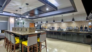 A modern kitchen with a central island, bar seating, and a variety of appliances.