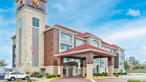 A hotel with a prominent tower, a covered entrance, and a parking area.