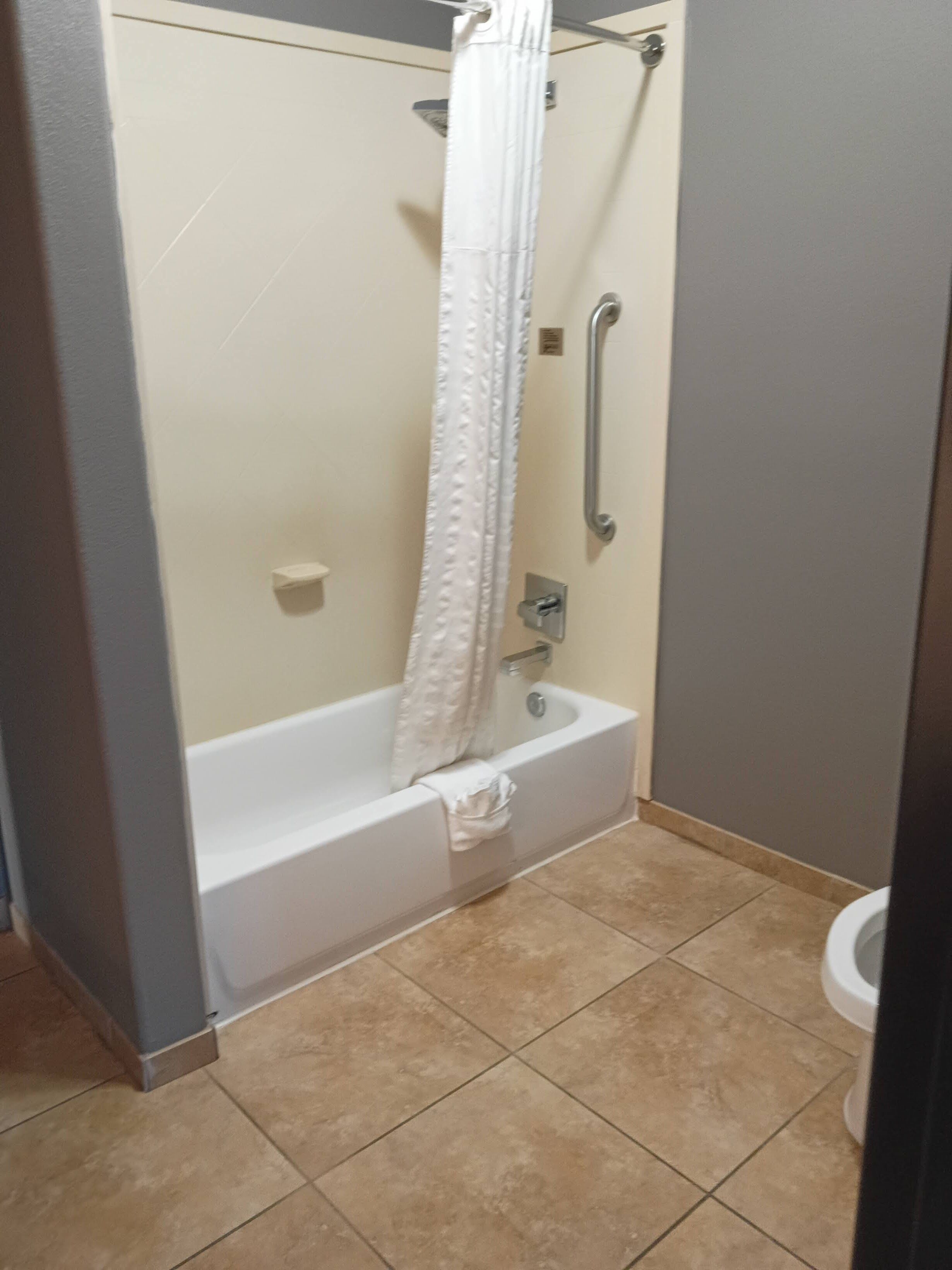A bathroom with a bathtub, a shower curtain, and a toilet.