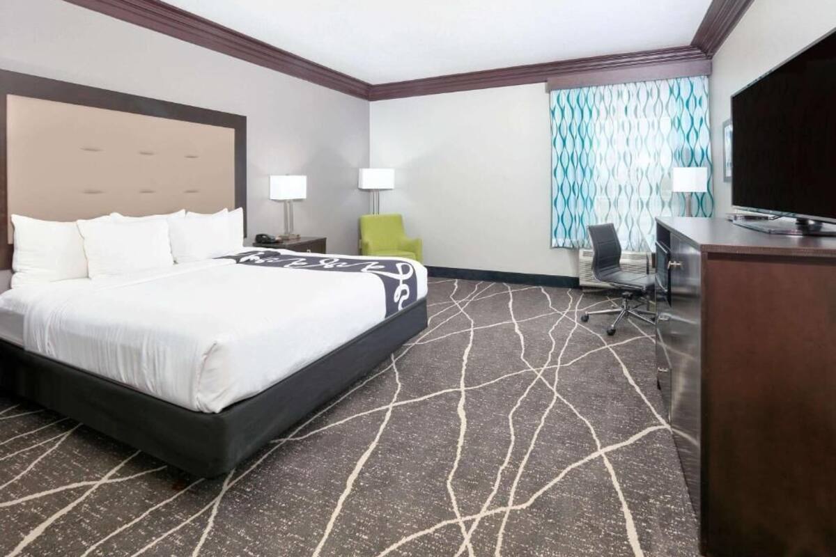 Una habitación de hotel con una cama grande, un escritorio, una silla y un televisor.