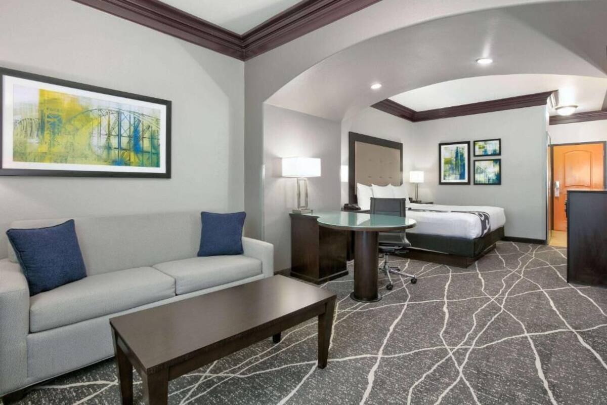 Una habitación de hotel con sofá, escritorio, cama y un cuadro grande en la pared.
