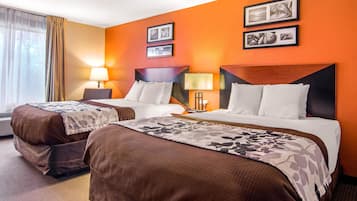 A hotel room with two beds, a large window with curtains, and a wall with framed pictures.