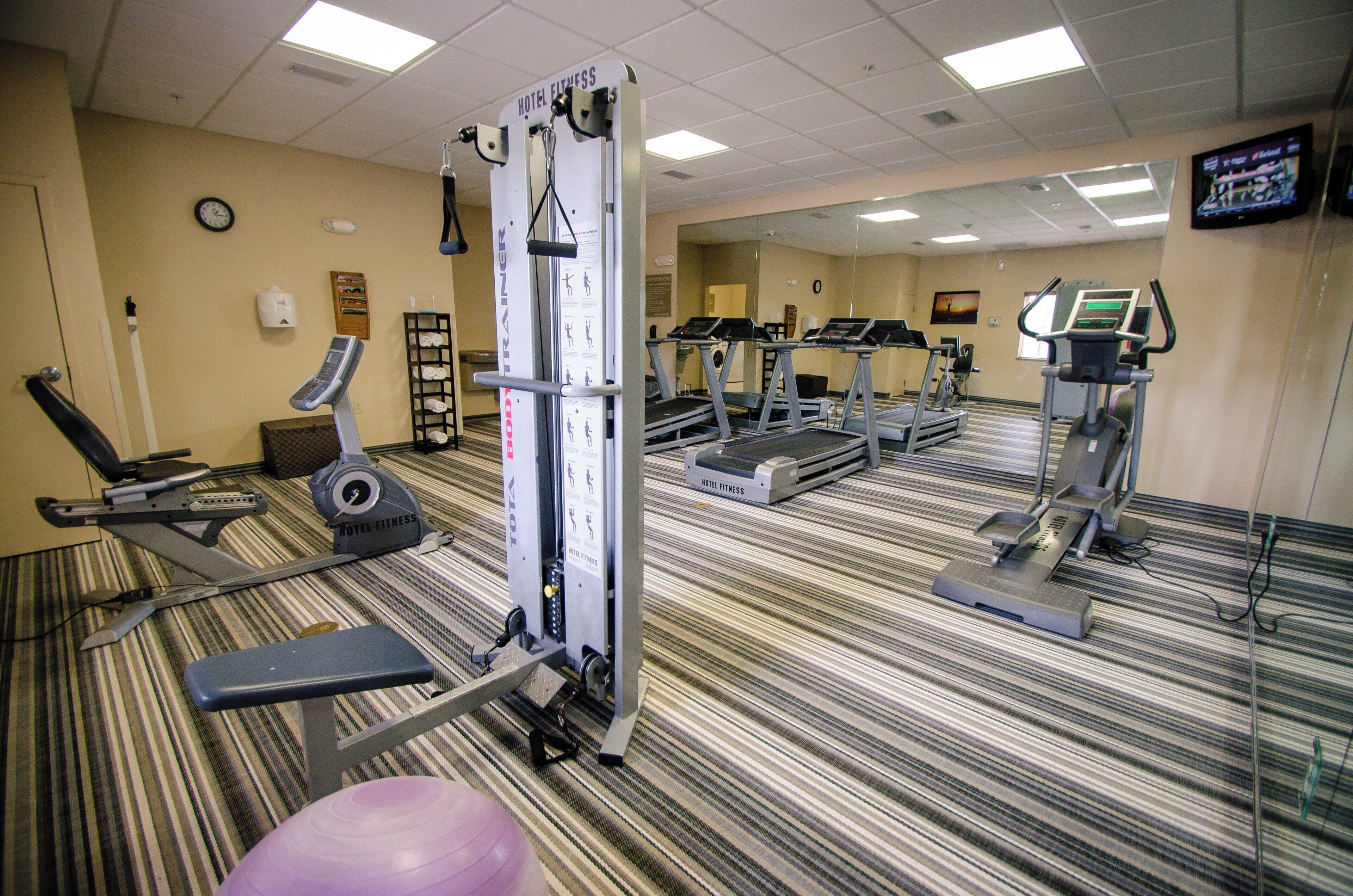 A hotel fitness center with treadmills, elliptical machines, and weight training equipment.