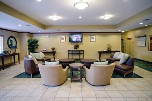 A hotel lobby with a seating area, a television, and a reception desk.