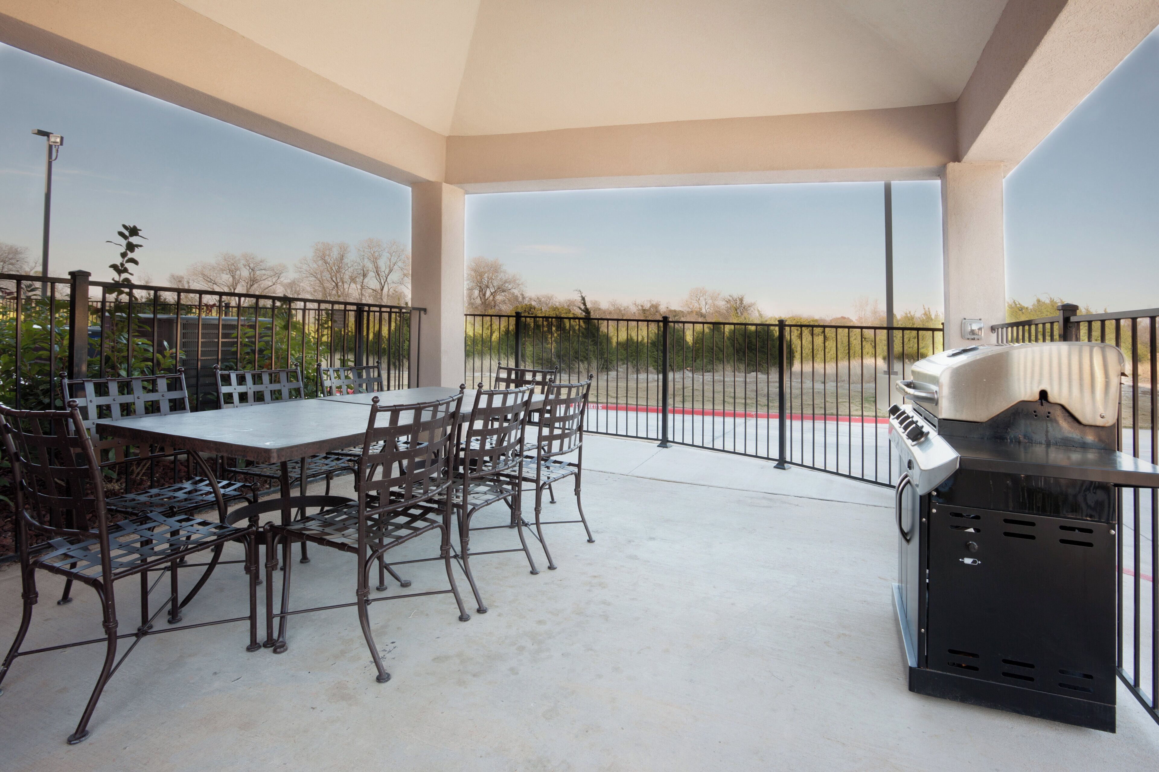 An outdoor patio with a table and chairs, a grill, and a view of the surrounding area.