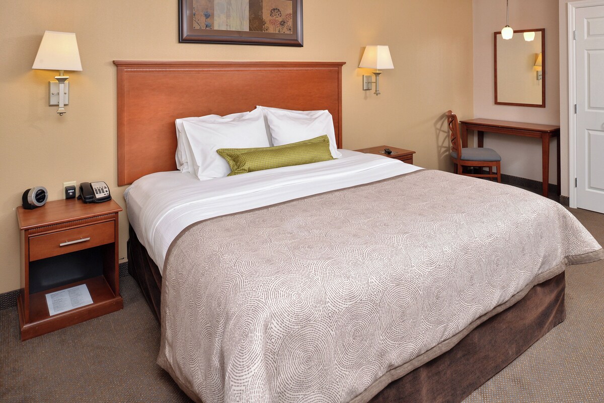 A hotel room with a large bed, two bedside tables, a desk, and a chair.
