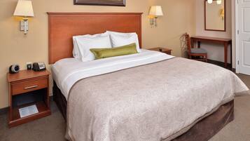 A hotel room with a large bed, two bedside tables, a desk, and a chair.