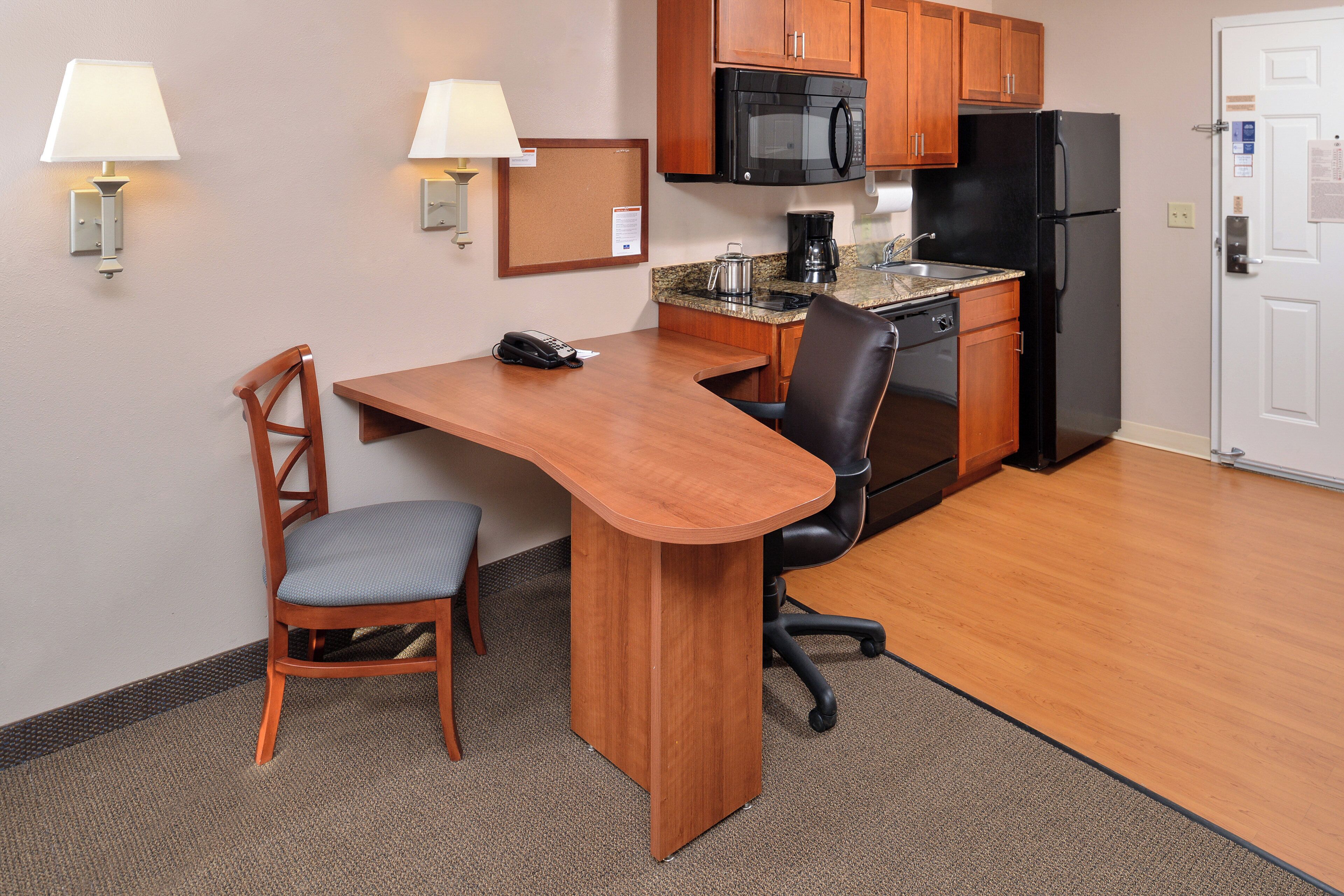A compact kitchen with a microwave, refrigerator, and a small dining area with a chair and table.