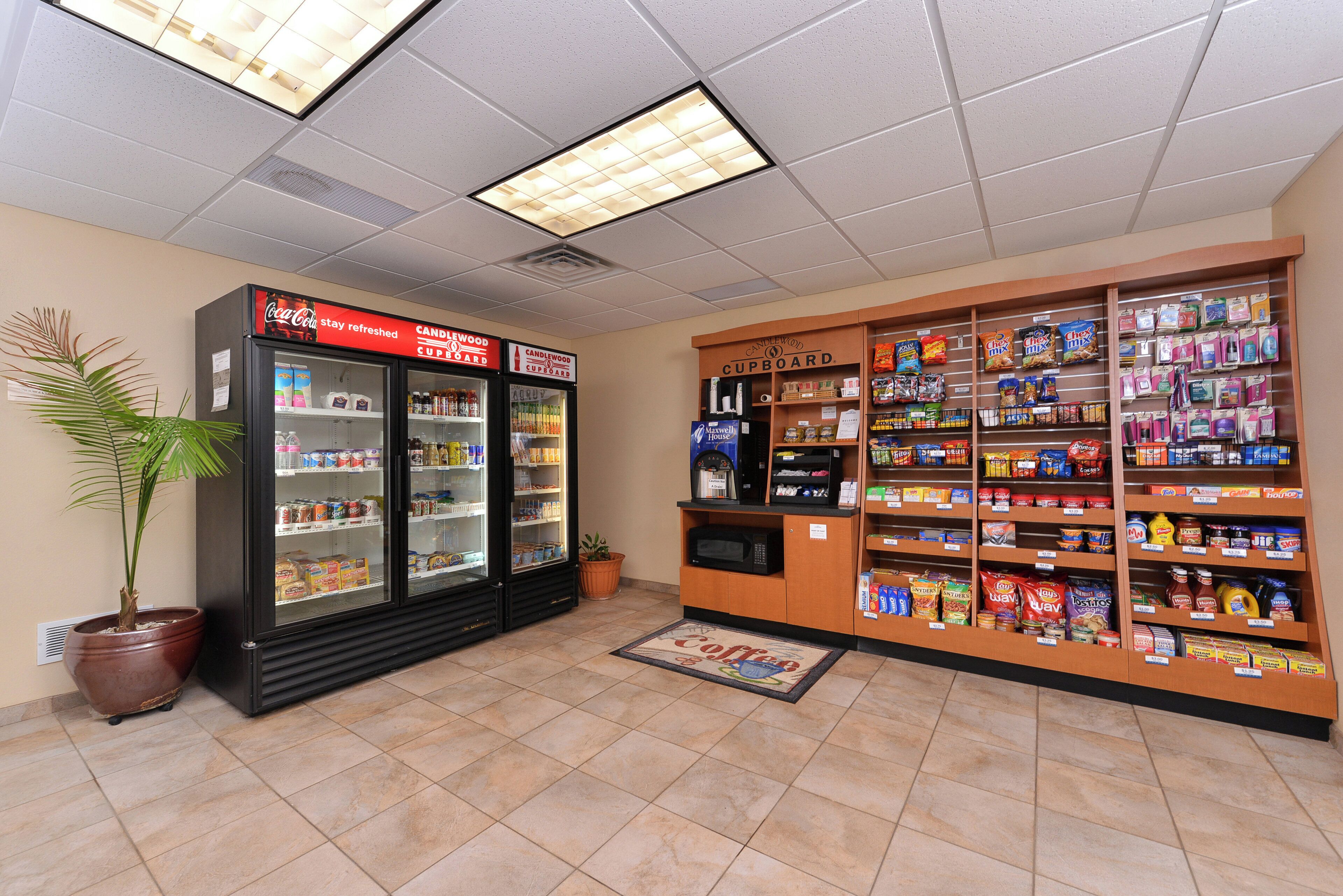 Una tienda de conveniencia con secciones refrigeradas, un microondas y estantes llenos de aperitivos y bebidas.