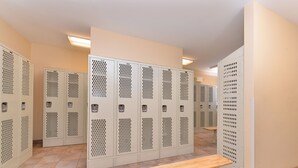 A row of lockers with a bench in the center, in a hallway with beige walls and tiled flooring. - Candlewood Suites Williston by IHG (Williston)