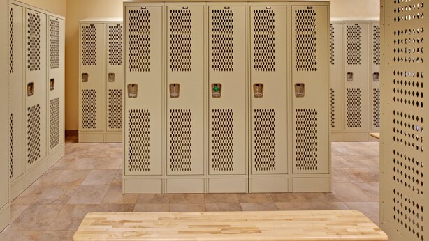 A row of beige lockers with a bench in front. - Candlewood Suites Williston by IHG (Williston)