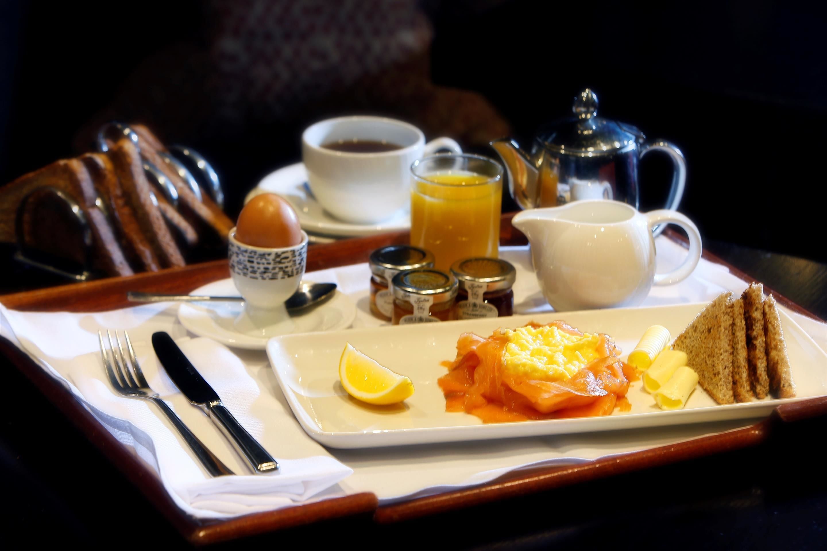 A breakfast tray with eggs, toast, butter, jam, and a cup of coffee.