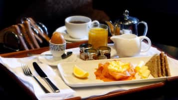 A breakfast tray with eggs, toast, butter, jam, and a cup of coffee.