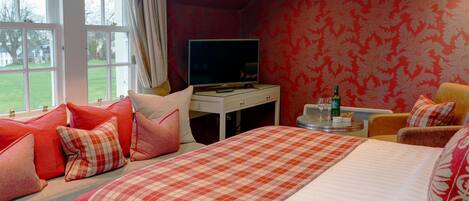 A hotel room with a large bed, a TV on a small table, and a view of the outdoors through a window.