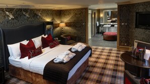 A spacious bedroom with a large bed, a sitting area, and a view into the bathroom. - Eglinton Arms Hotel, BW Premier Collection (Glasgow)