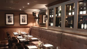 A restaurant with a long dining table, cushioned booths, and a bar area with bottles. - Eglinton Arms Hotel, BW Premier Collection (Glasgow)