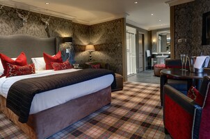 Una habitación de hotel con una cama grande, una mesita de noche, una silla y una mesa con lámpara.